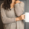 Woman wearing Harvest bead gold necklace and gold bracelets holding mug