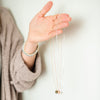 Woman holding gold, rose gold, and silver rainbow stamped necklaces