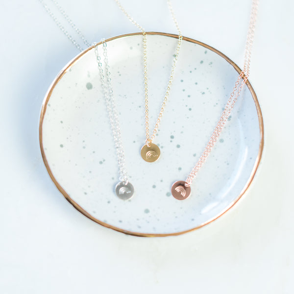 Rainbow stamped silver, gold, and rose gold necklaces laying in bowl