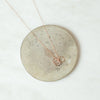 Trio rose gold ring necklace on coaster